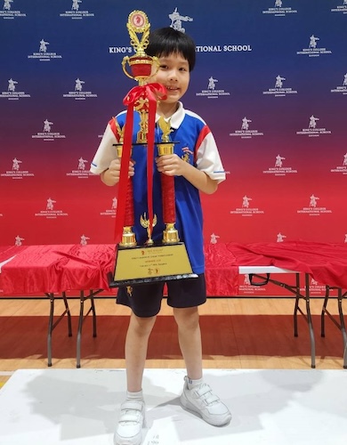 A young boy with a huge trophy at the King's Bangkok Chess Championship