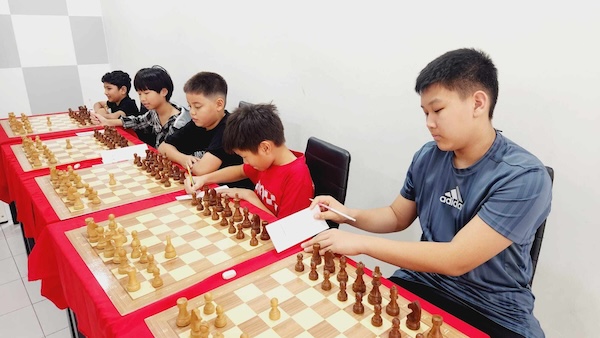 Kids with Grandmaster Vladimir Lazarev joins Riste at Red Knight Chess Club for a simul event.