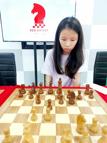 A very young girl playing chess against Grandmaster Vladimir Lazarev at Red Knight Chess Club for a simul event.