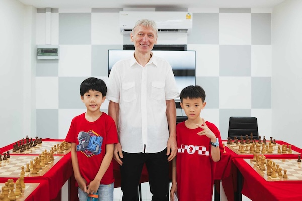 Grandmaster Vladimir Lazarev joins two young boys at the Red Knight Chess Club for a simul event.