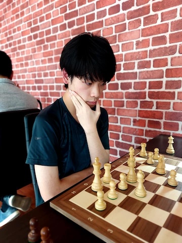 Boy thinking hard while playing chess at the Red Knight Chess Club in Bangkok.