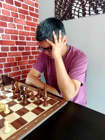 Boy in deep thought while playing chess at the Red Knight Chess Club in Bangkok.