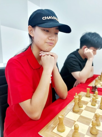 Girl playing chess at the Red Knight Chess Club in Bangkok.