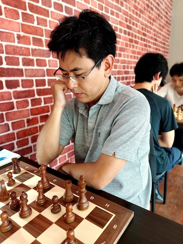 Man with glasses playing chess at the Red Knight Chess Club in Bangkok.